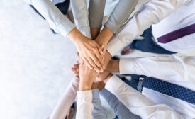 Close up top view of young business people putting their hands together