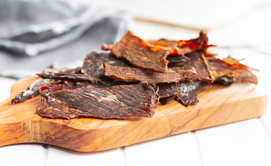 Beef jerky meat. Dried sliced meat on a wooden cutting board.