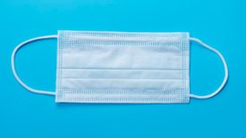 Disposable face mask on blue background