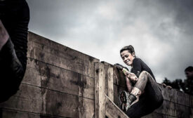 Woman Climbing Wall in Tough Mudder Race